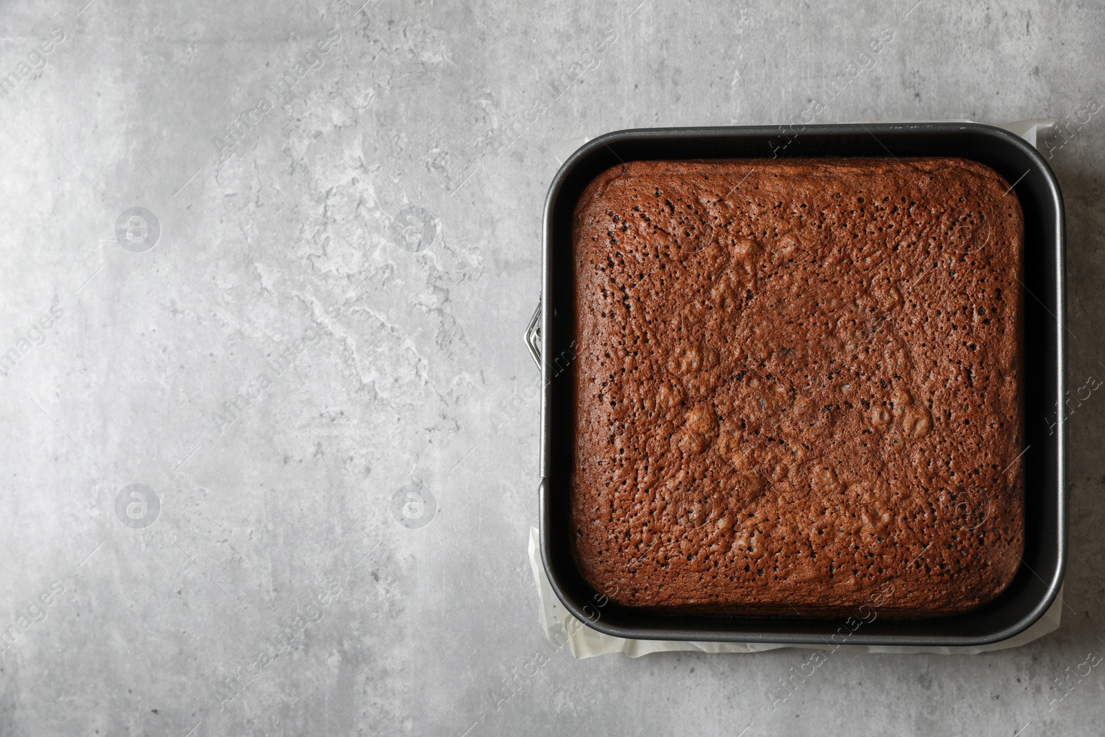 Photo of Homemade chocolate sponge cake on light grey table, top view. Space for text