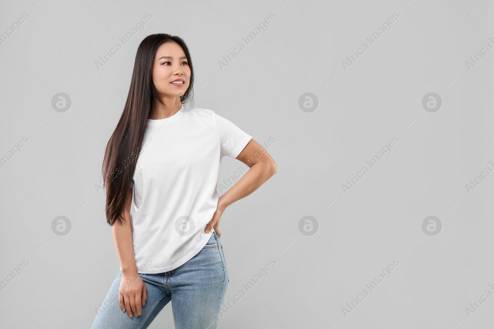 Photo of Woman wearing white t-shirt on light grey background, space for text