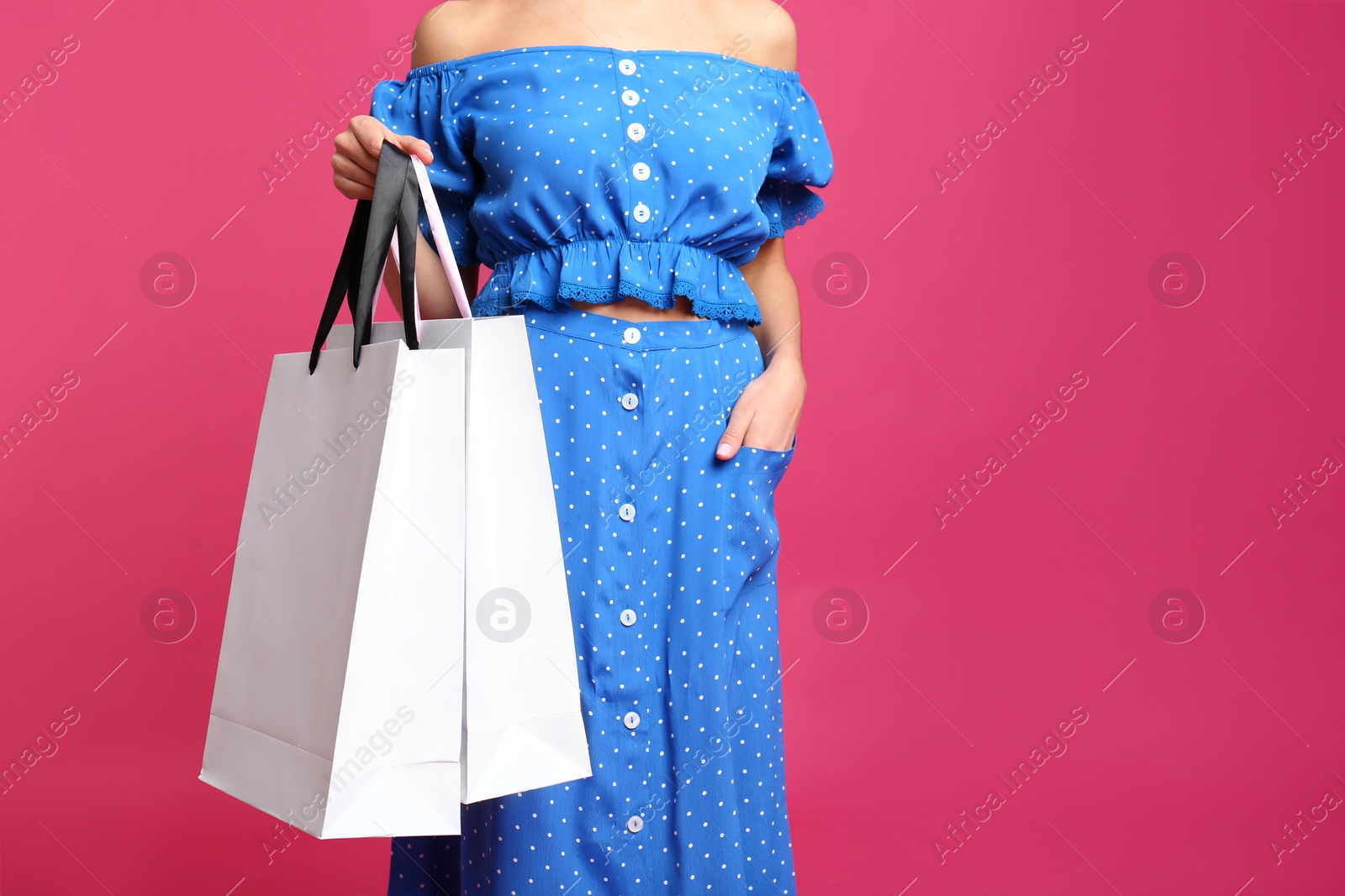 Photo of Young woman with paper bags on pink background, closeup. Space for text