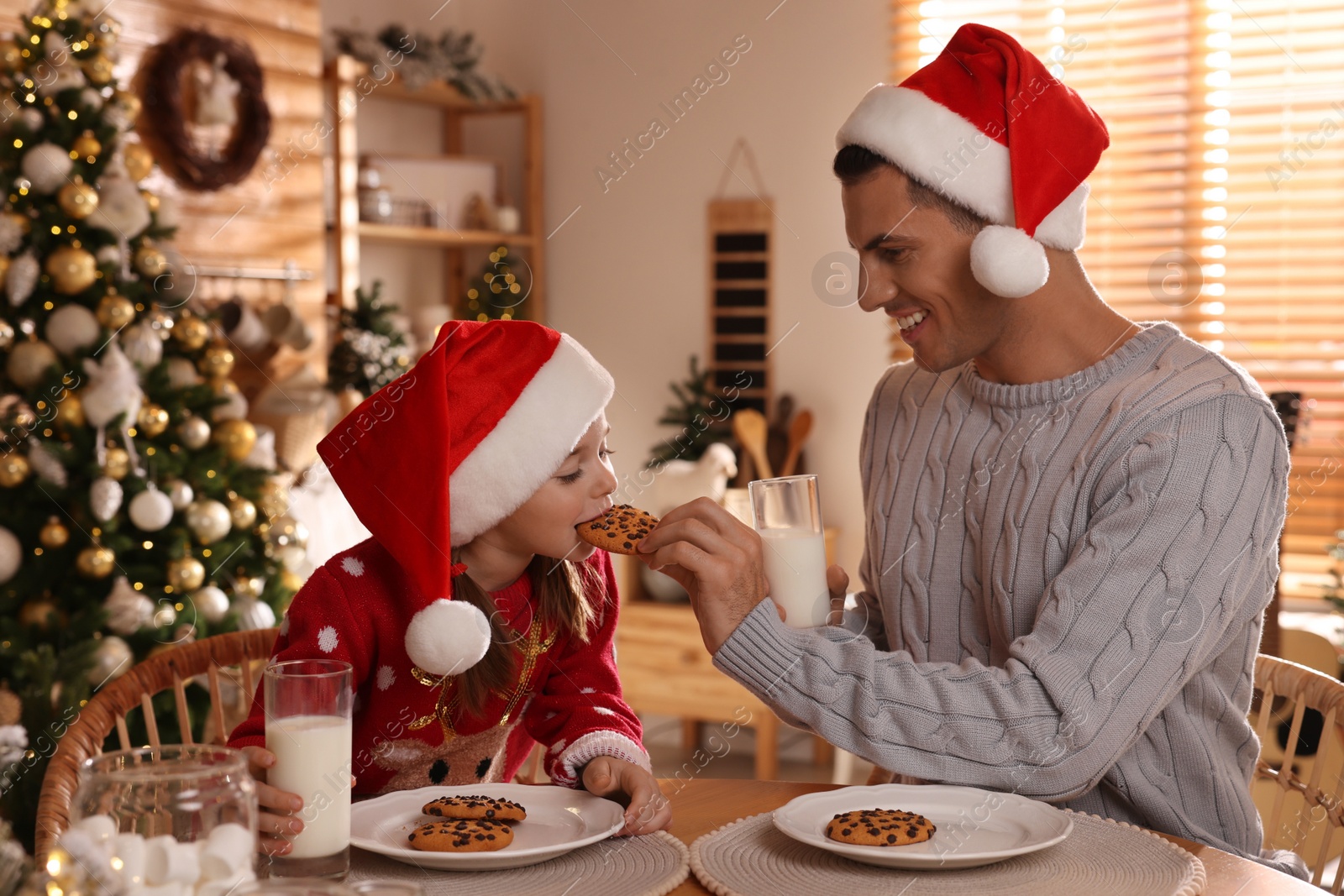 Photo of Happy father and his daughter eating delicious Christmas cookies at home