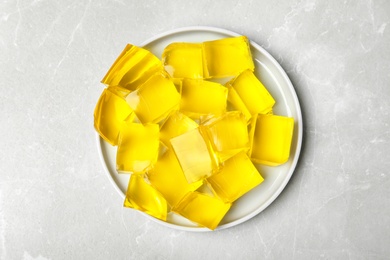 Photo of Plate of delicious lemon jelly on light table, top view