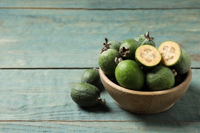 Photo of Fresh green feijoa fruits on blue wooden table, space for text