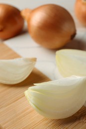 Photo of Whole and cut onions on white table, closeup