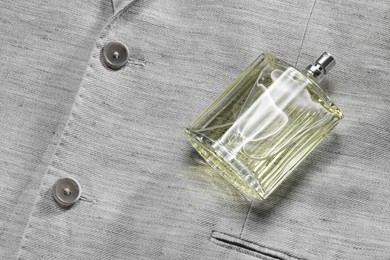 Photo of Luxury men's perfume in bottle on grey jacket, space for text