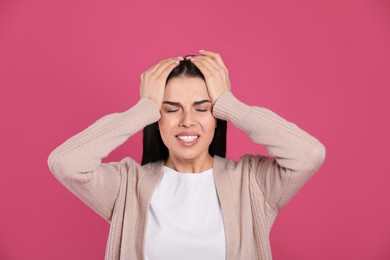 Photo of Woman suffering from migraine on pink background