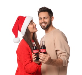 Photo of MYKOLAIV, UKRAINE - JANUARY 27, 2021: Young couple holding bottles of Coca-Cola on white background. Christmas atmosphere