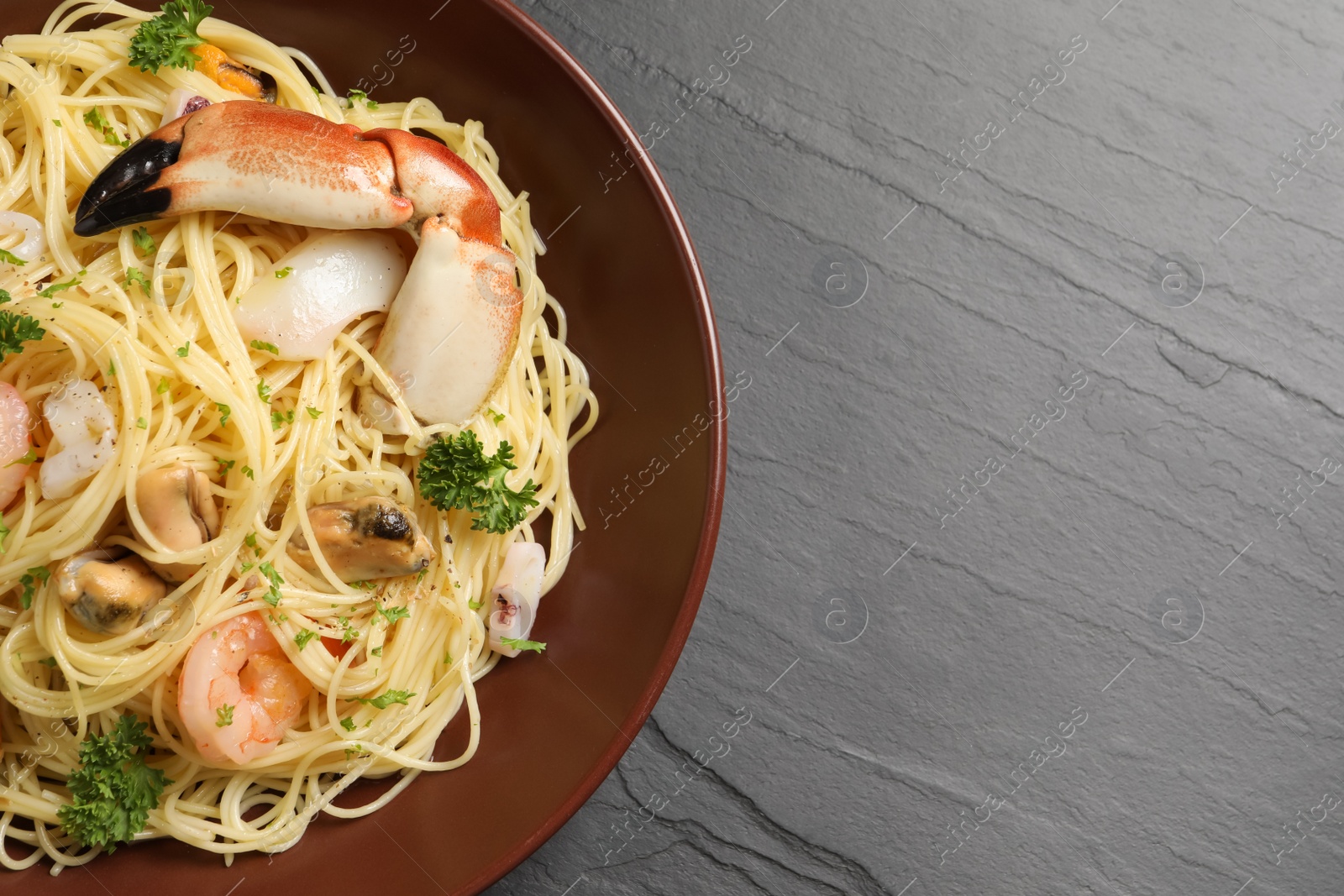 Photo of Delicious pasta with sea food on black table, top view. Space for text