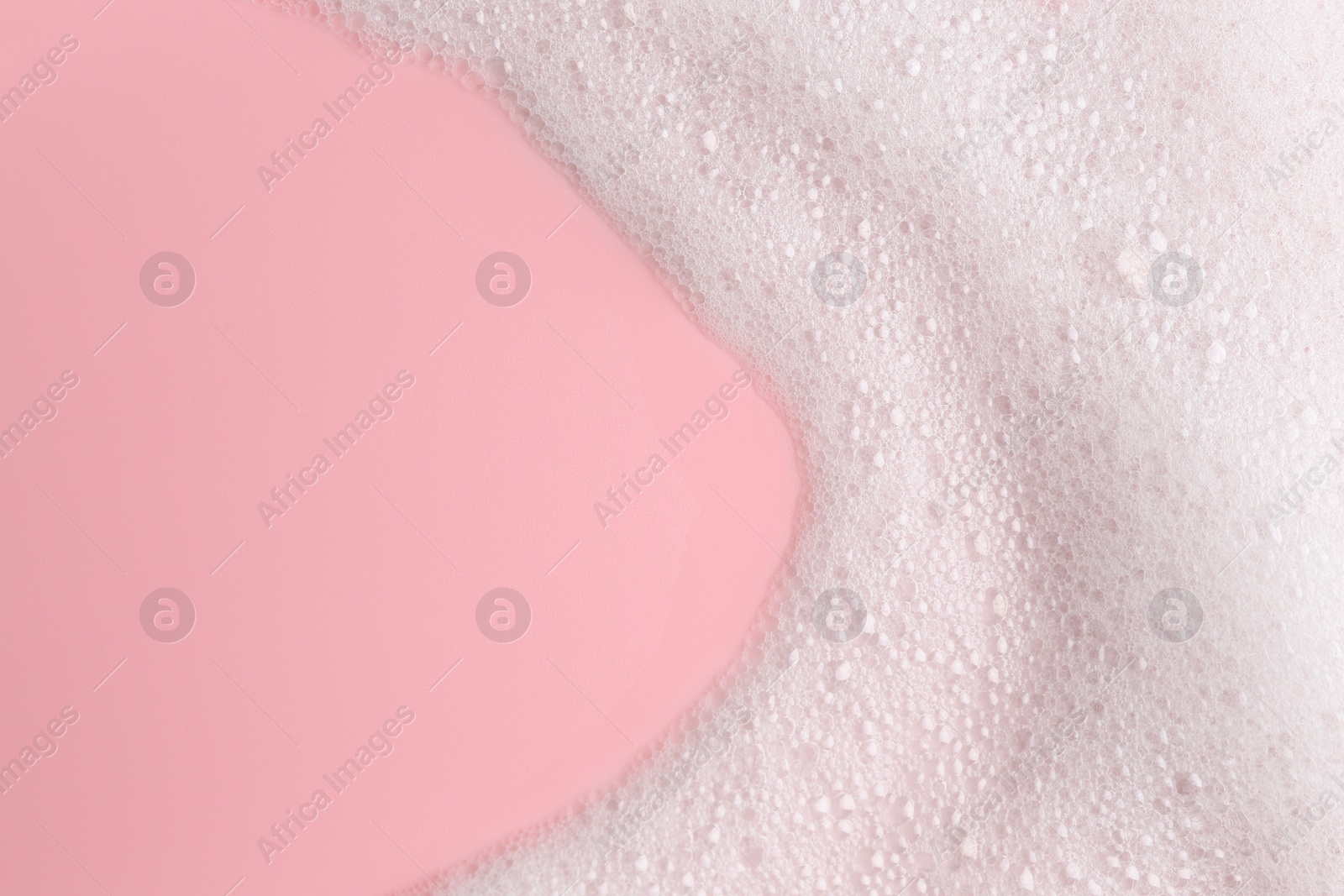 Photo of White fluffy foam on pink background, top view. Space for text