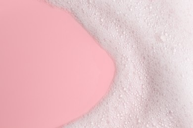 Photo of White fluffy foam on pink background, top view. Space for text