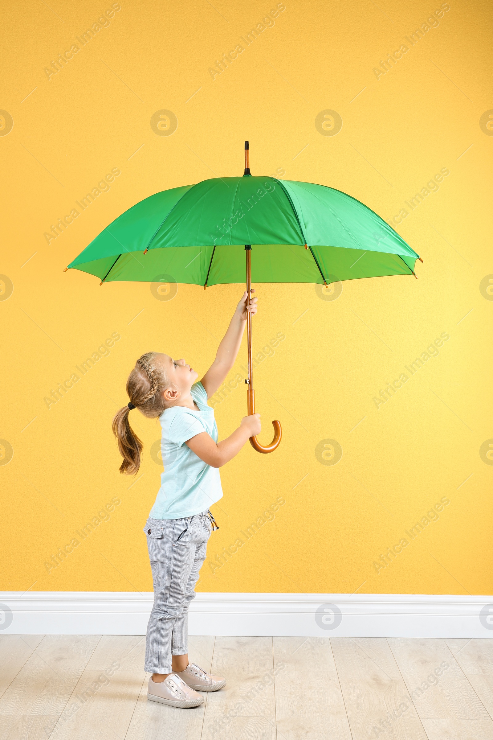 Photo of Little girl with green umbrella near color wall