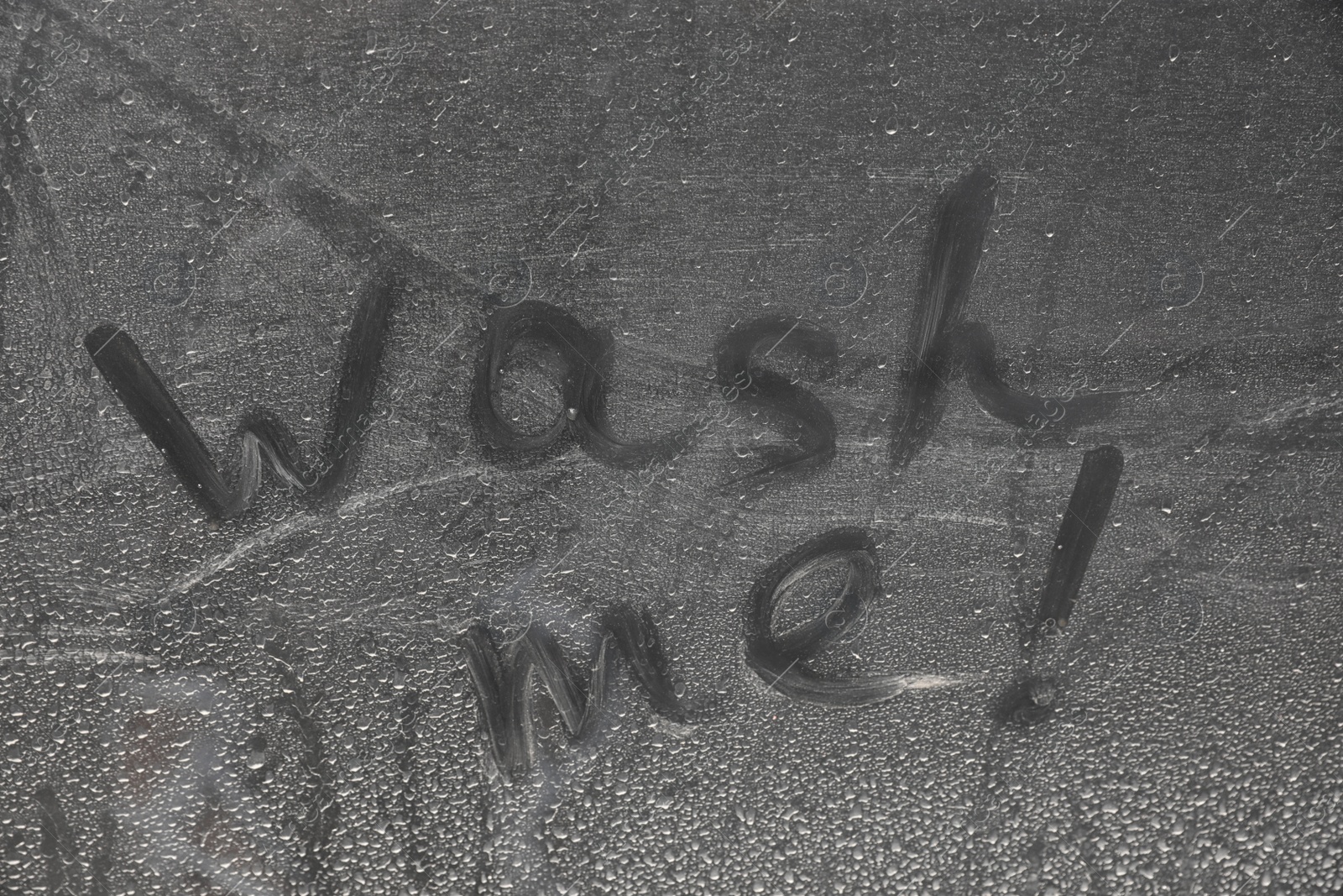 Photo of Inscription WASH ME on car window, closeup