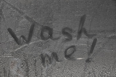 Photo of Inscription WASH ME on car window, closeup