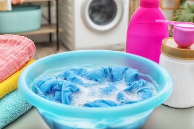 Color clothes with foam in basin and detergents on table in bathroom