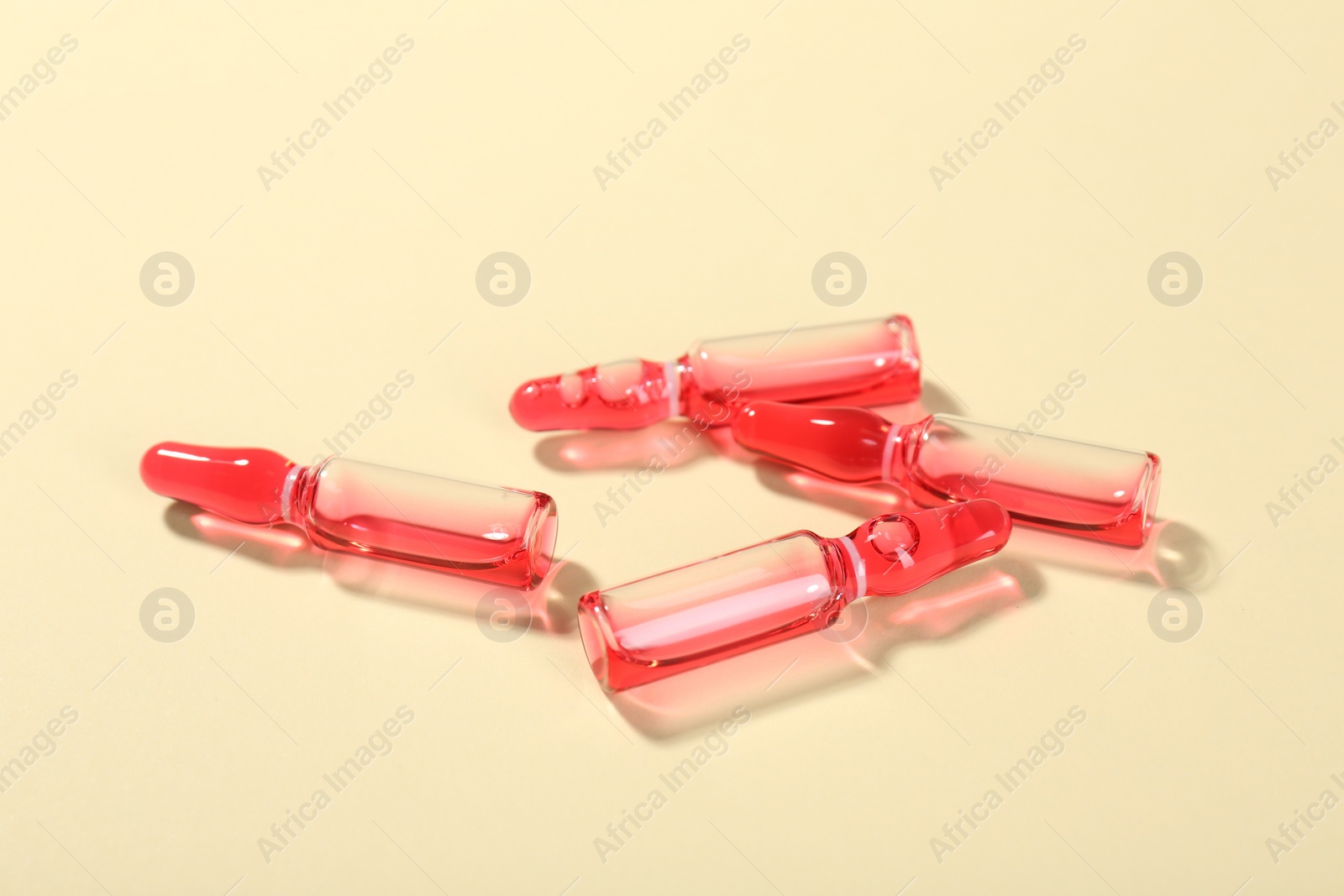 Photo of Glass ampoules with liquid on beige background