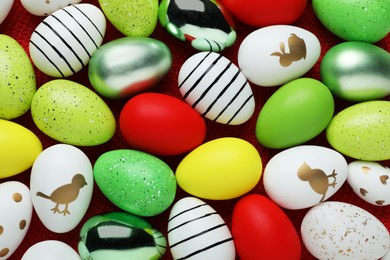 Photo of Many beautifully decorated Easter eggs on red background, flat lay