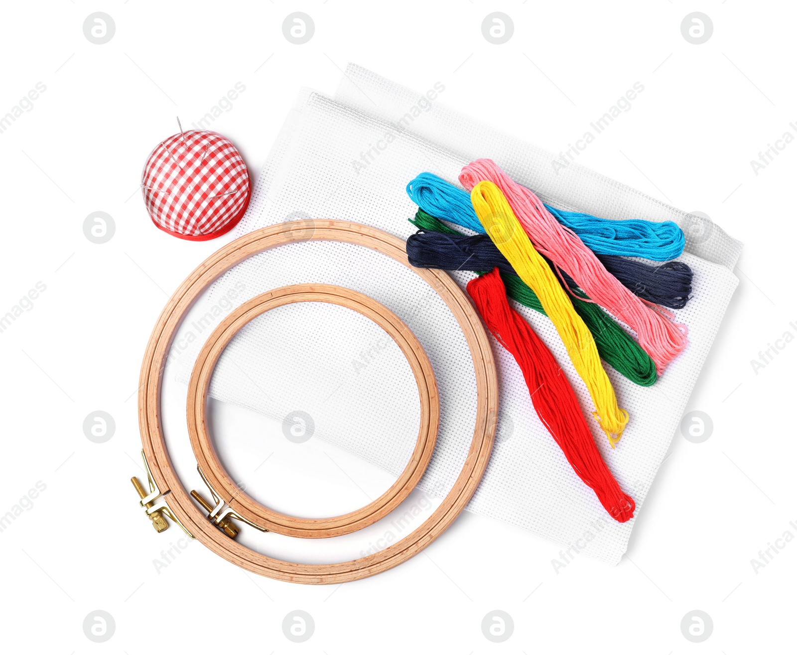Photo of Colorful threads and different embroidery accessories on white background, top view