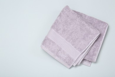 Photo of Violet terry towel on light grey background, top view. Space for text