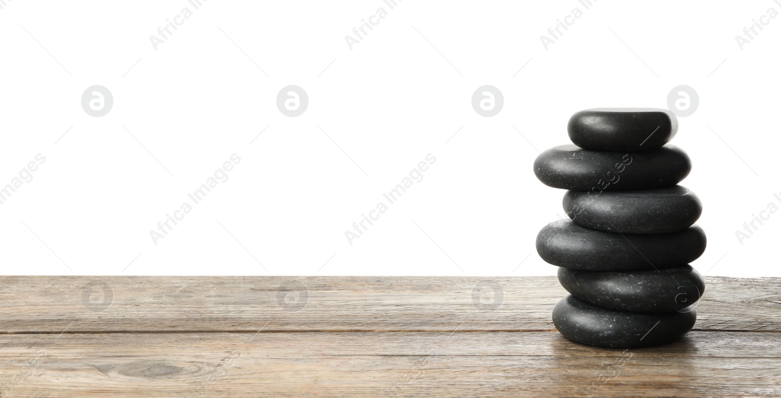 Photo of Stack of spa stones on wooden table against white background. Space for text