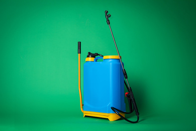 Photo of Manual insecticide sprayer on green background. Pest control