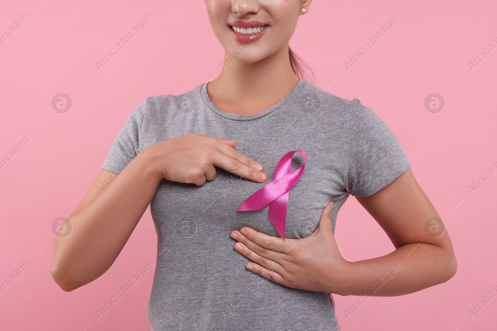 Photo of Woman with pink ribbon on color background, closeup. Breast cancer awareness