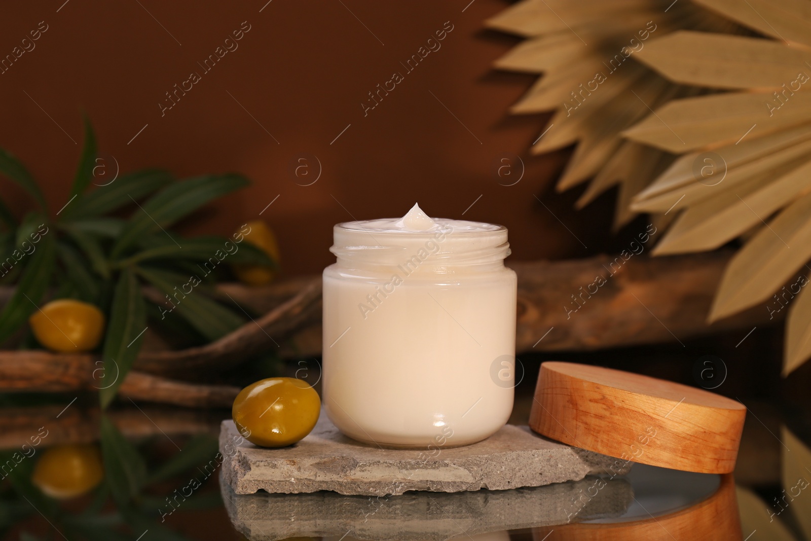 Photo of Jar of cream and olives on glass table