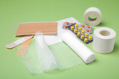 Photo of White bandage and medical supplies on light green background