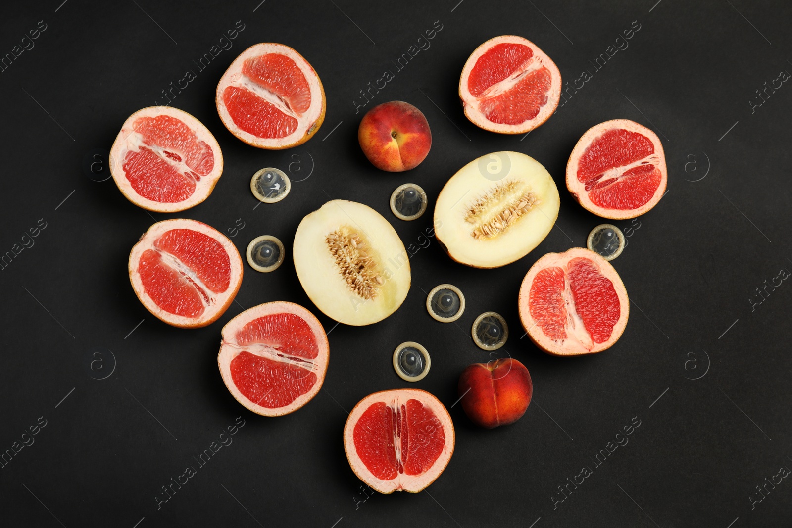 Photo of Flat lay composition with condoms and exotic fruits on black background. Erotic concept