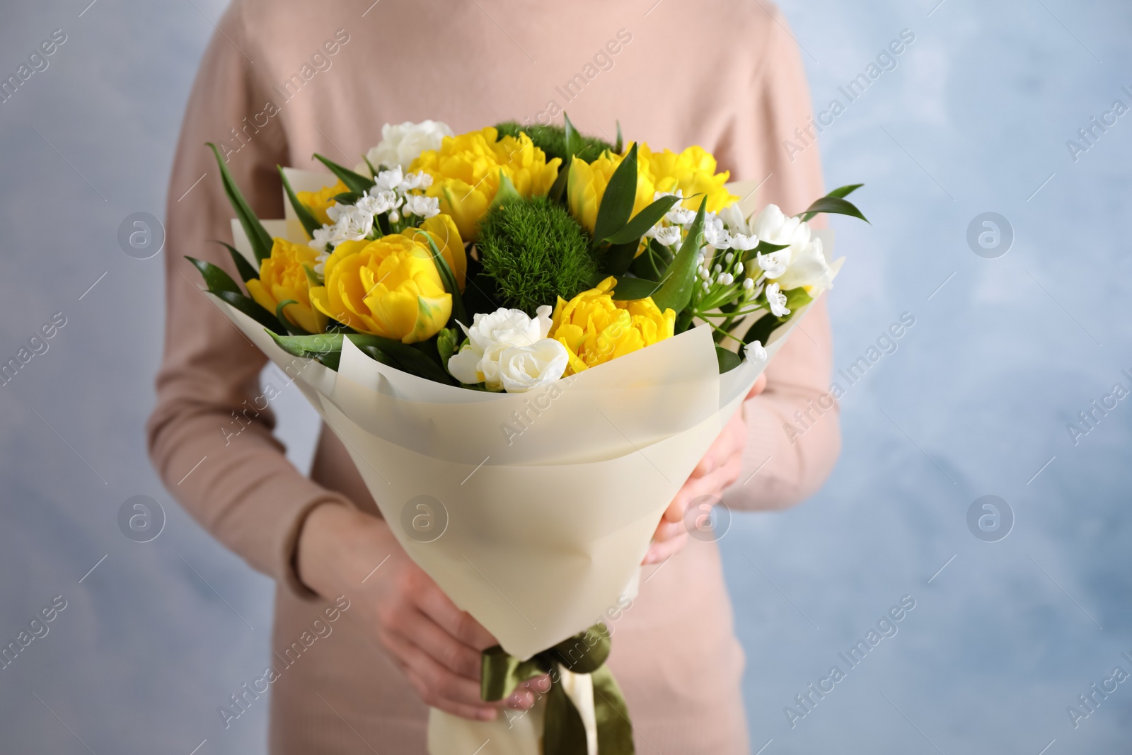 Photo of Woman with bouquet of beautiful tulips on light blue background, closeup
