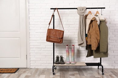 Photo of Stylish hallway interior with shoes and clothes on hanger stand