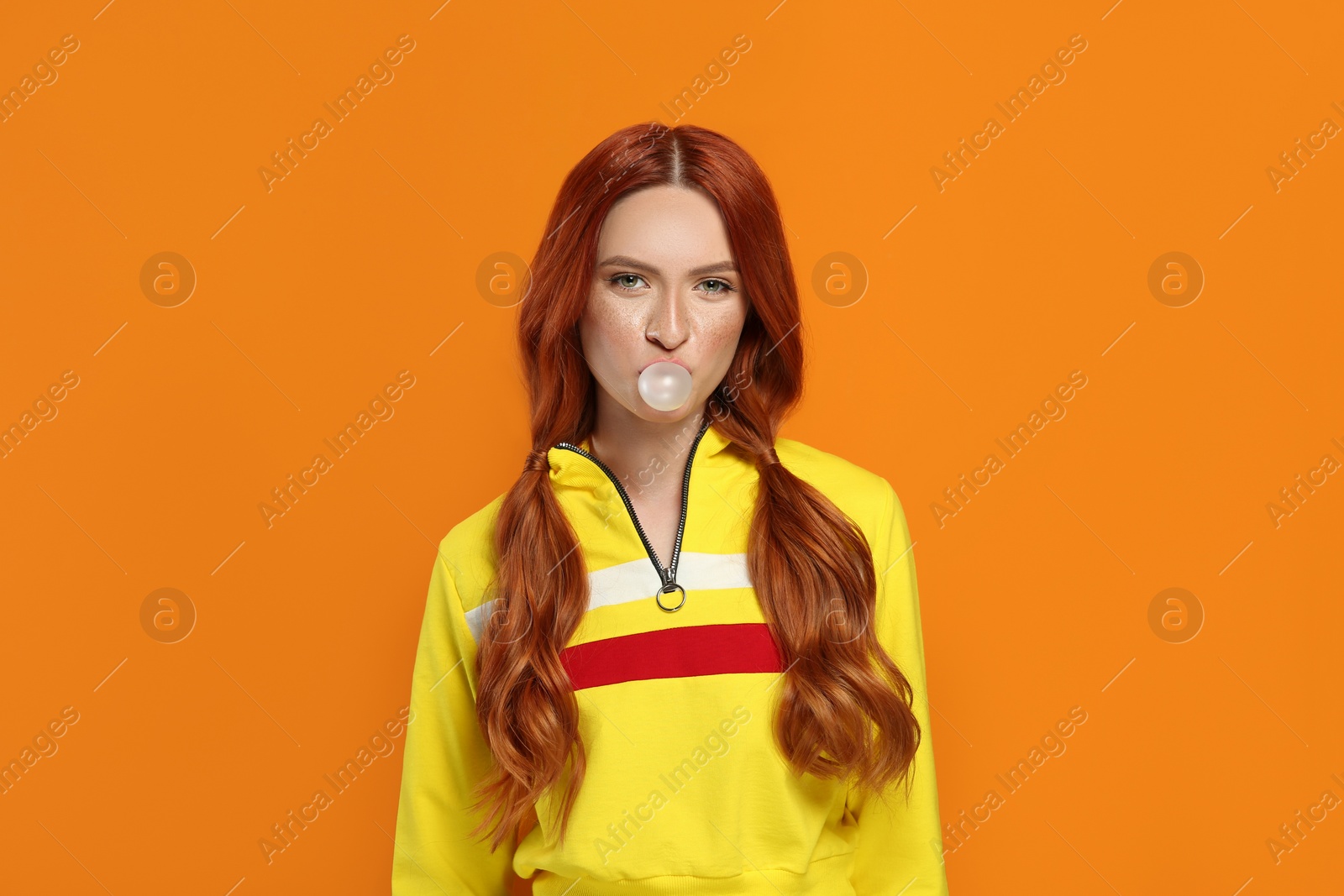 Photo of Portrait of beautiful woman blowing bubble gum on orange background