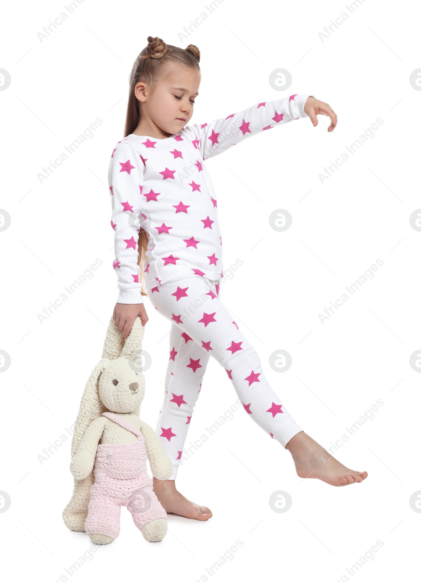 Photo of Girl in pajamas with toy bunny sleepwalking on white background