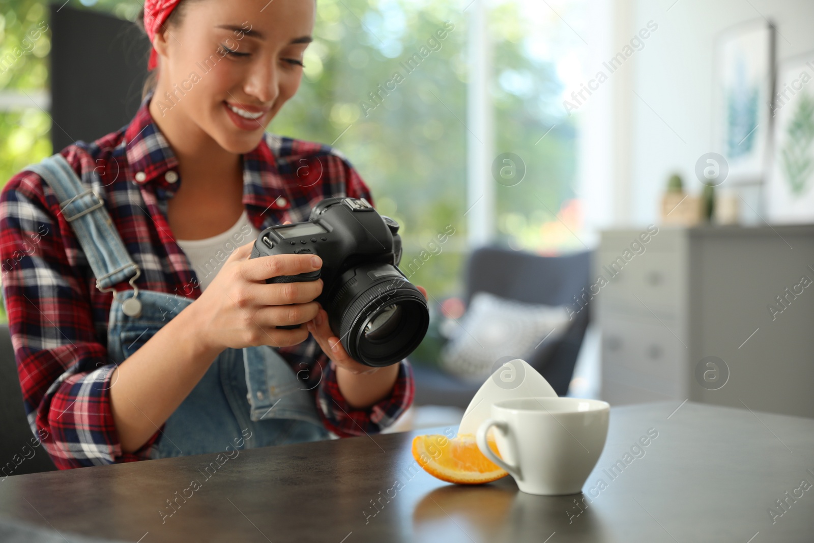Photo of Young photographer taking picture of cups at table indoors, closeup