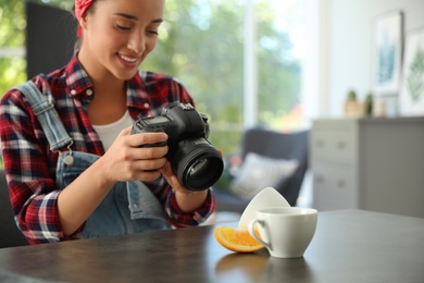 Photo of Young photographer taking picture of cups at table indoors, closeup