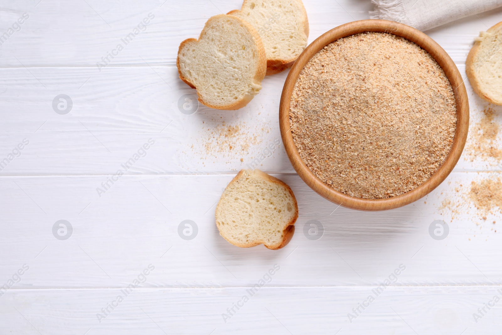 Photo of Fresh breadcrumbs in bowl on white wooden table, flat lay. Space for text