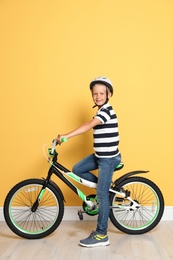 Photo of Portrait of cute little boy with bicycle near color wall