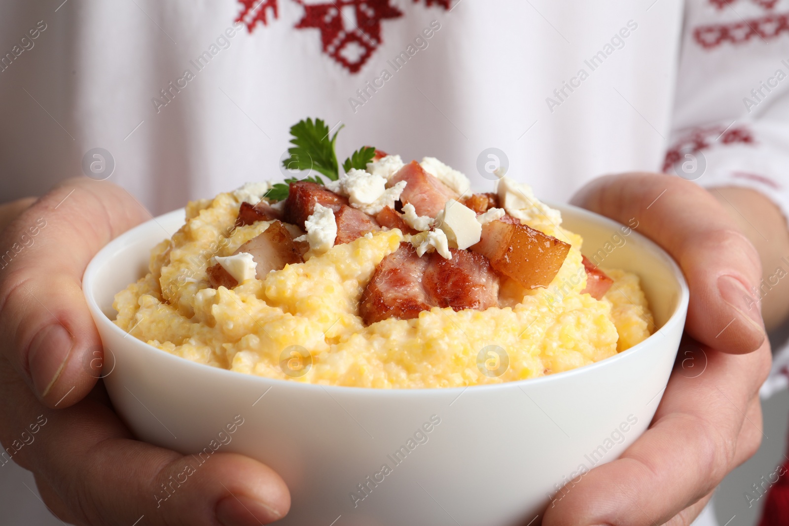 Photo of Woman holding bowl of delicious traditional Ukrainian banosh, closeup