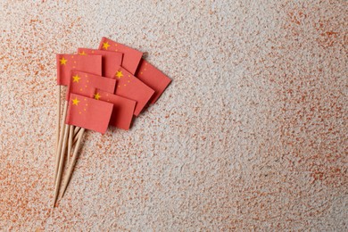 Small paper flags of China on color textured background, flat lay. Space for text