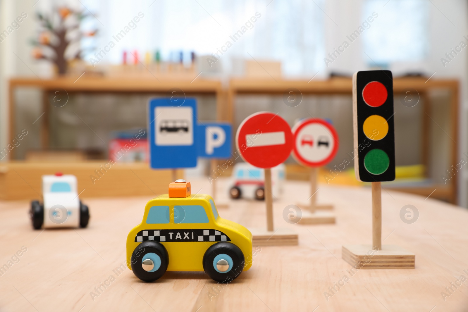 Photo of Different miniature road signs and cars on wooden table. Montessori toy