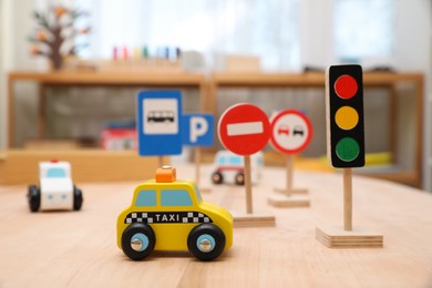 Photo of Different miniature road signs and cars on wooden table. Montessori toy