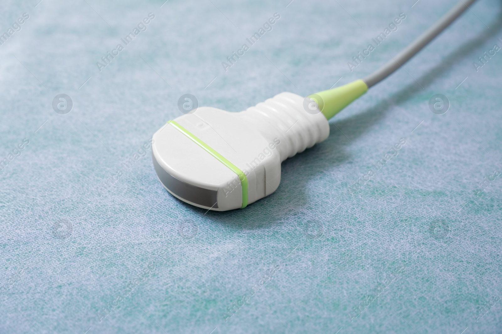 Photo of Ultrasonic transducer on green examination table, closeup. Ultrasound device