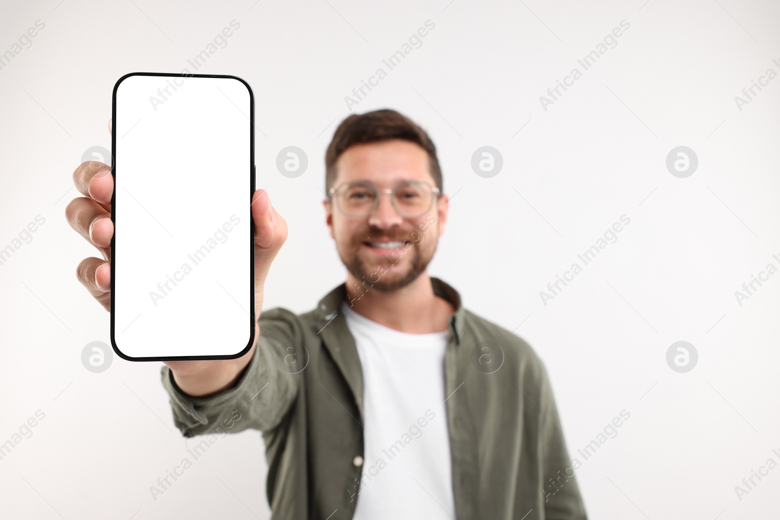 Photo of Handsome man showing smartphone in hand on white background, selective focus. Mockup for design