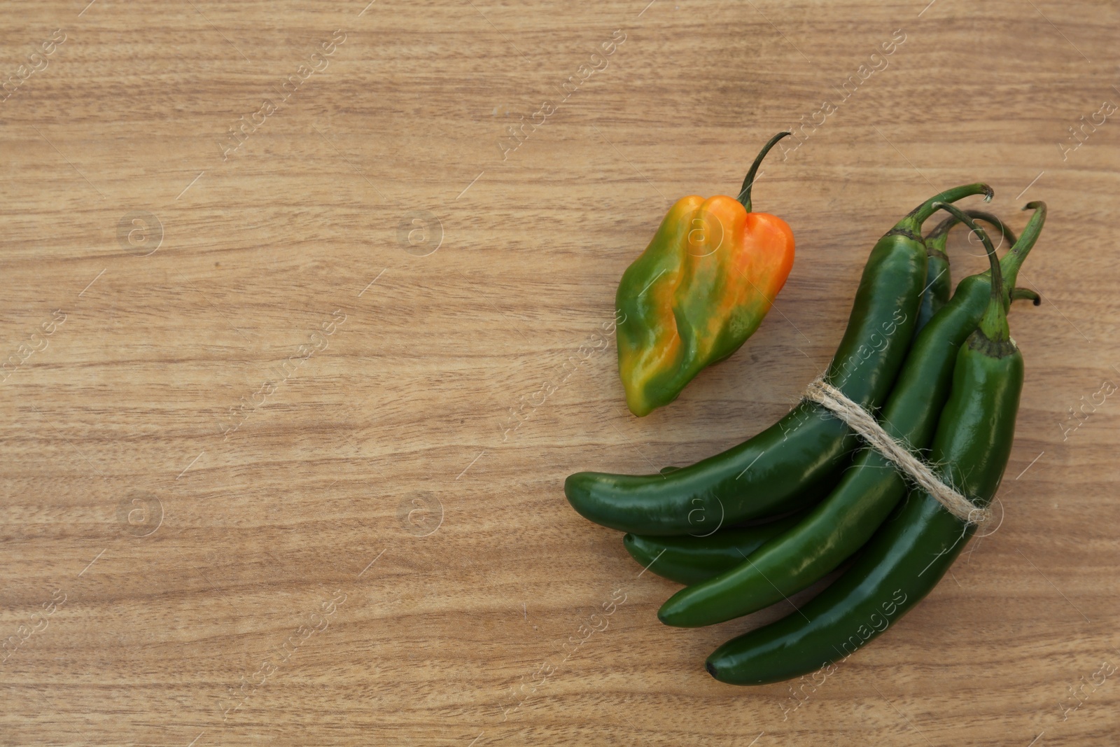 Photo of Different fresh ripe peppers on wooden table, flat lay. Space for text