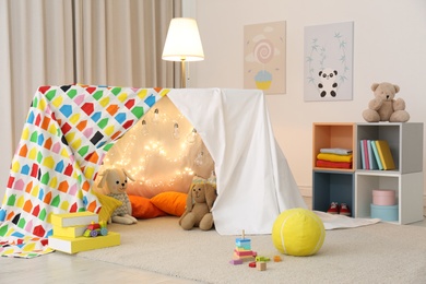 Photo of Play tent decorated with festive lights in modern child's room