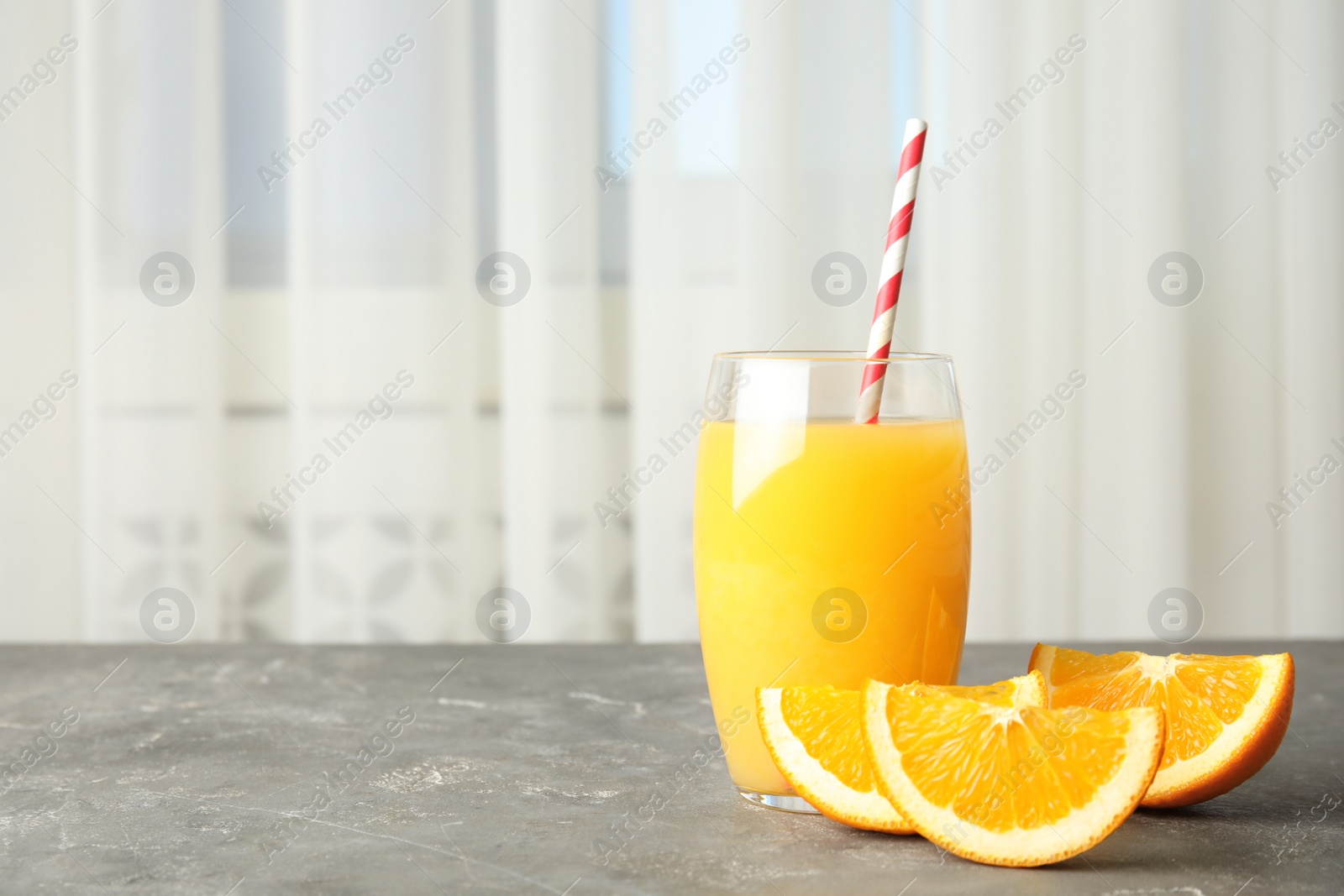 Photo of Glass with orange juice and fresh fruit on table, space for text