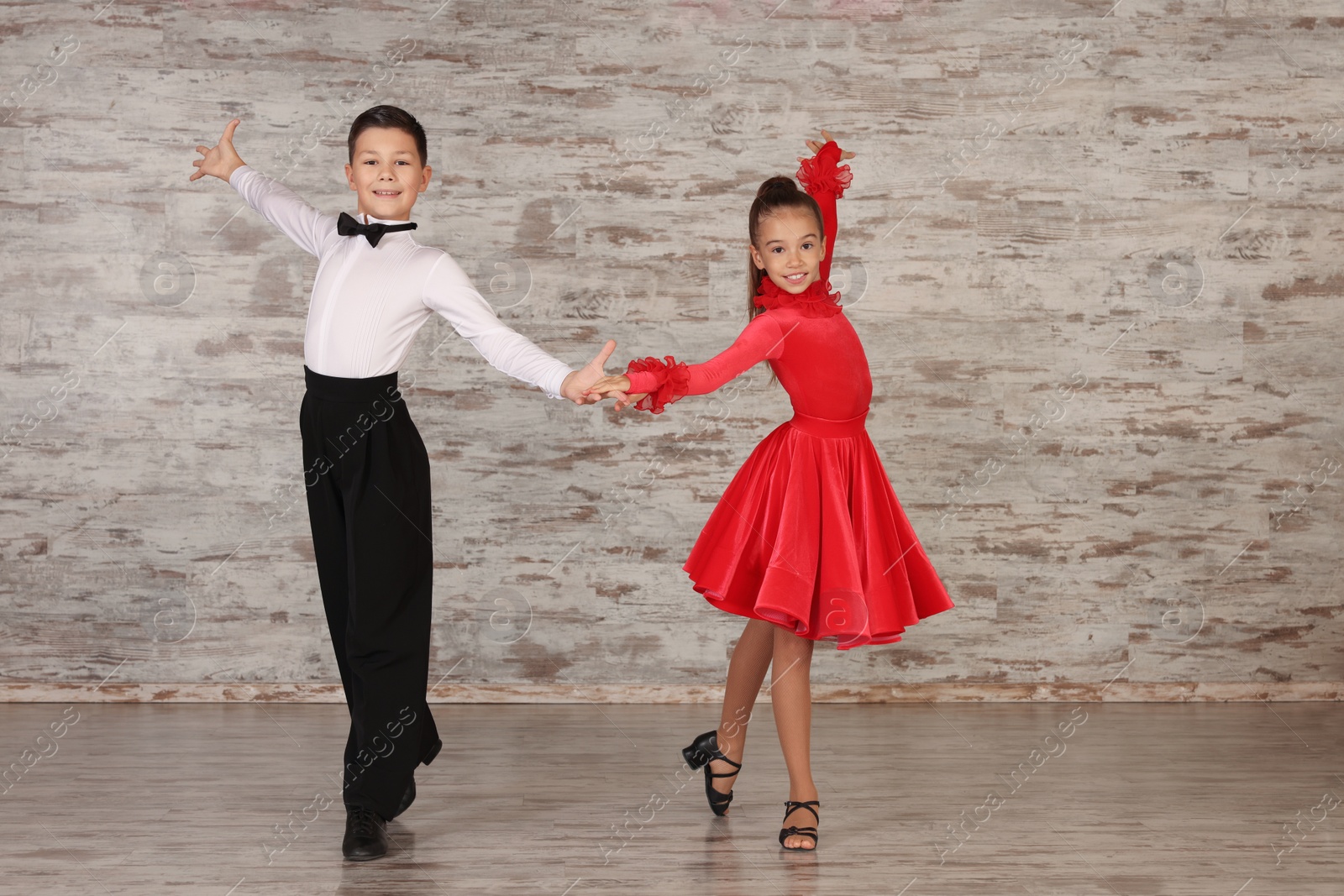 Photo of Beautifully dressed couple of kids dancing together in studio