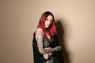 Photo of Beautiful woman with tattoos on body against beige background