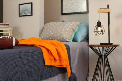 Photo of Stylish teenager's room interior with comfortable bed, lamp and football ball