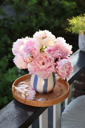 Photo of Beautiful pink peony flowers in vase on balcony railing outdoors