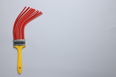 Photo of Brush with red straws on light grey background, top view. Space for text. Creative concept