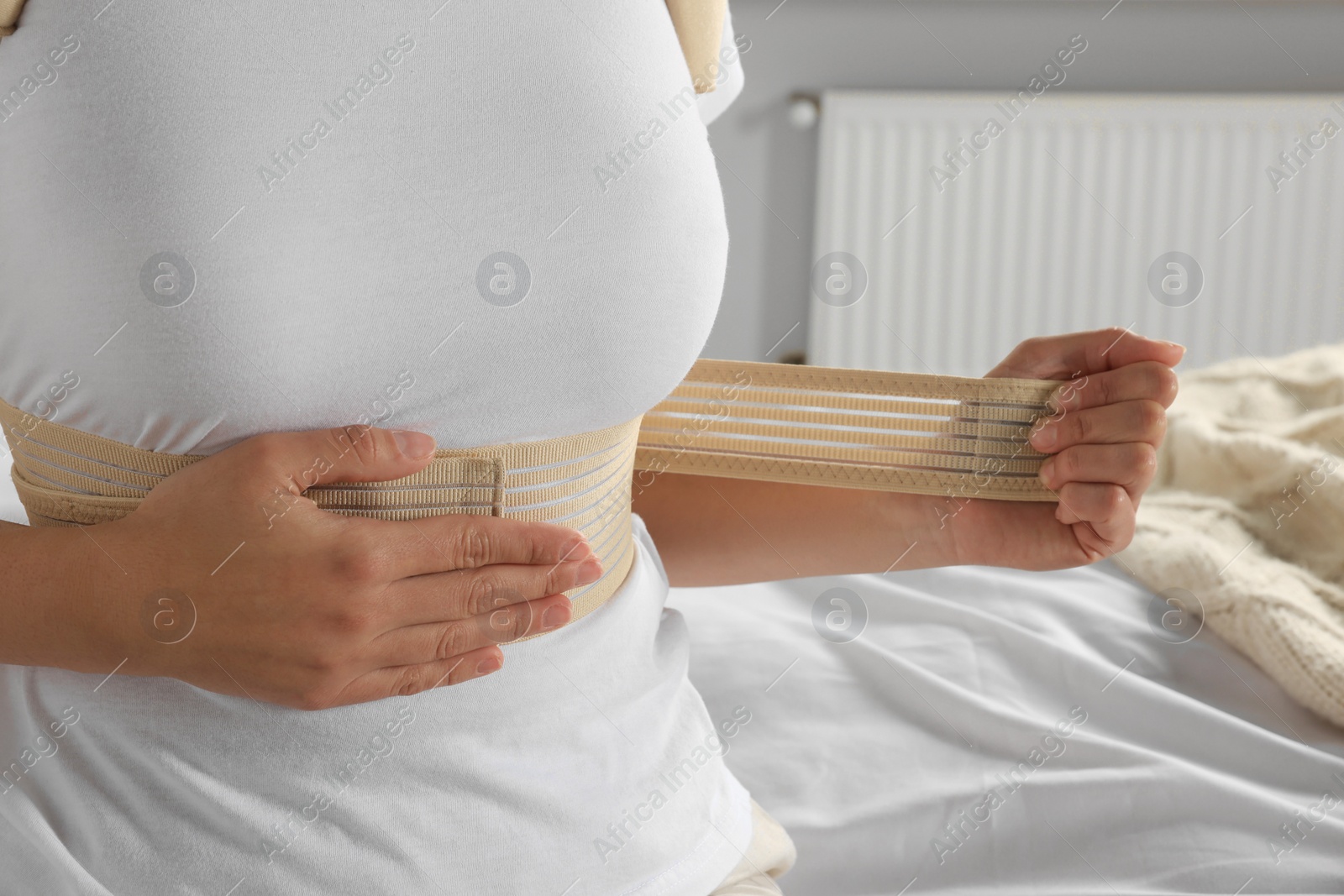 Photo of Woman with orthopedic corset sitting in bedroom, closeup